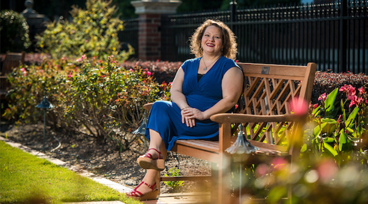 Renee smiling and sitting on a bench outdoors