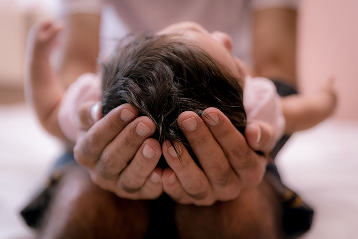 Baby's head being cradled in father's hands