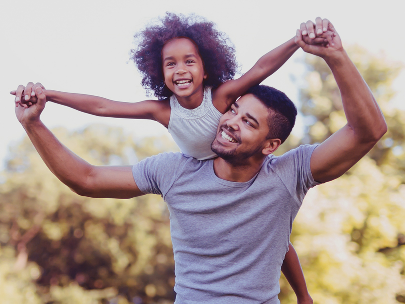 Father and daughter in front of trees